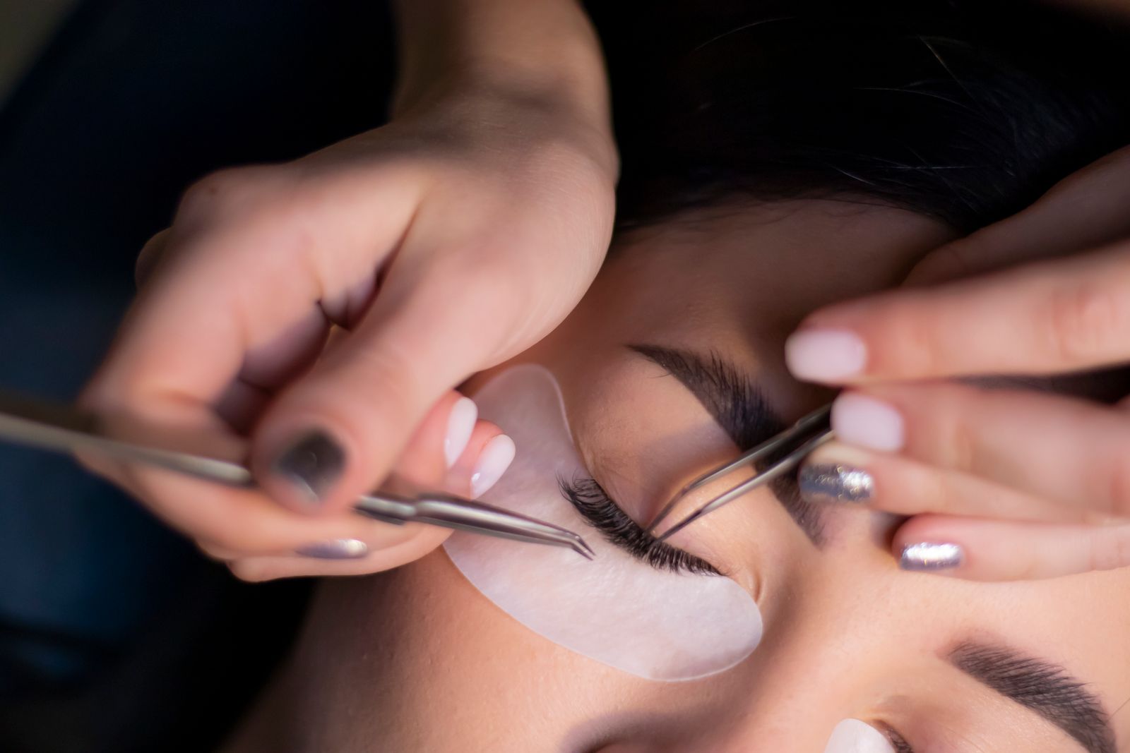 Close-up of a lash artist placing extensions with tweezers